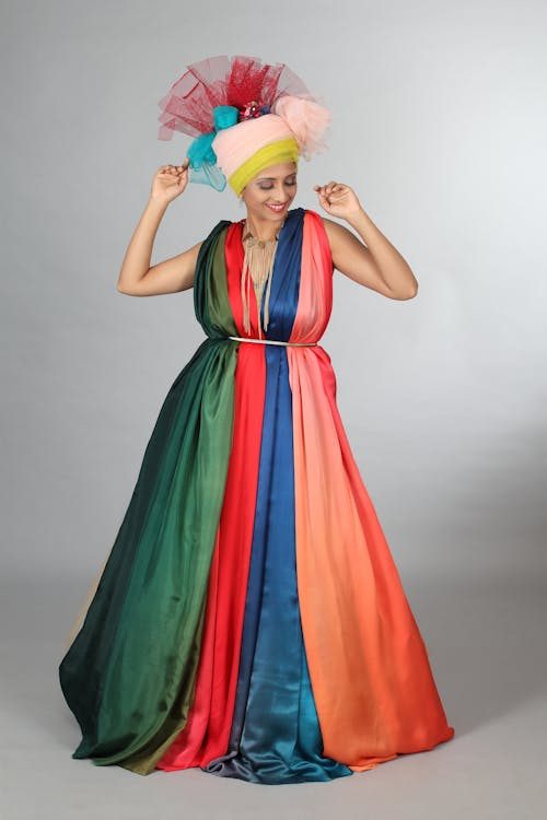 Woman in a vibrant colour-blocked dress and bold headpiece illustrating the 2026 trend of confident colour-blocked millinery