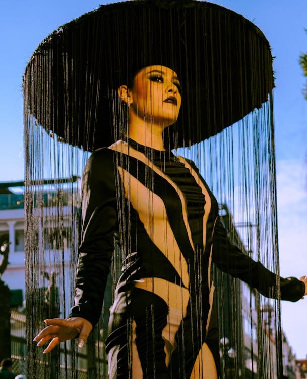 Model in a bold fringed statement hat captured outdoors showcasing how a dramatic headpiece commands attention