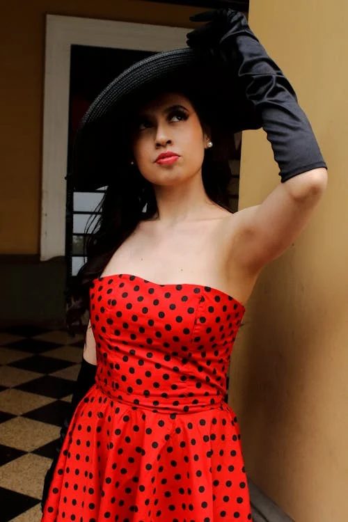 Vintage-inspired fashion portrait of a woman in a polka dot dress and statement hat illustrating bold pattern and classic form