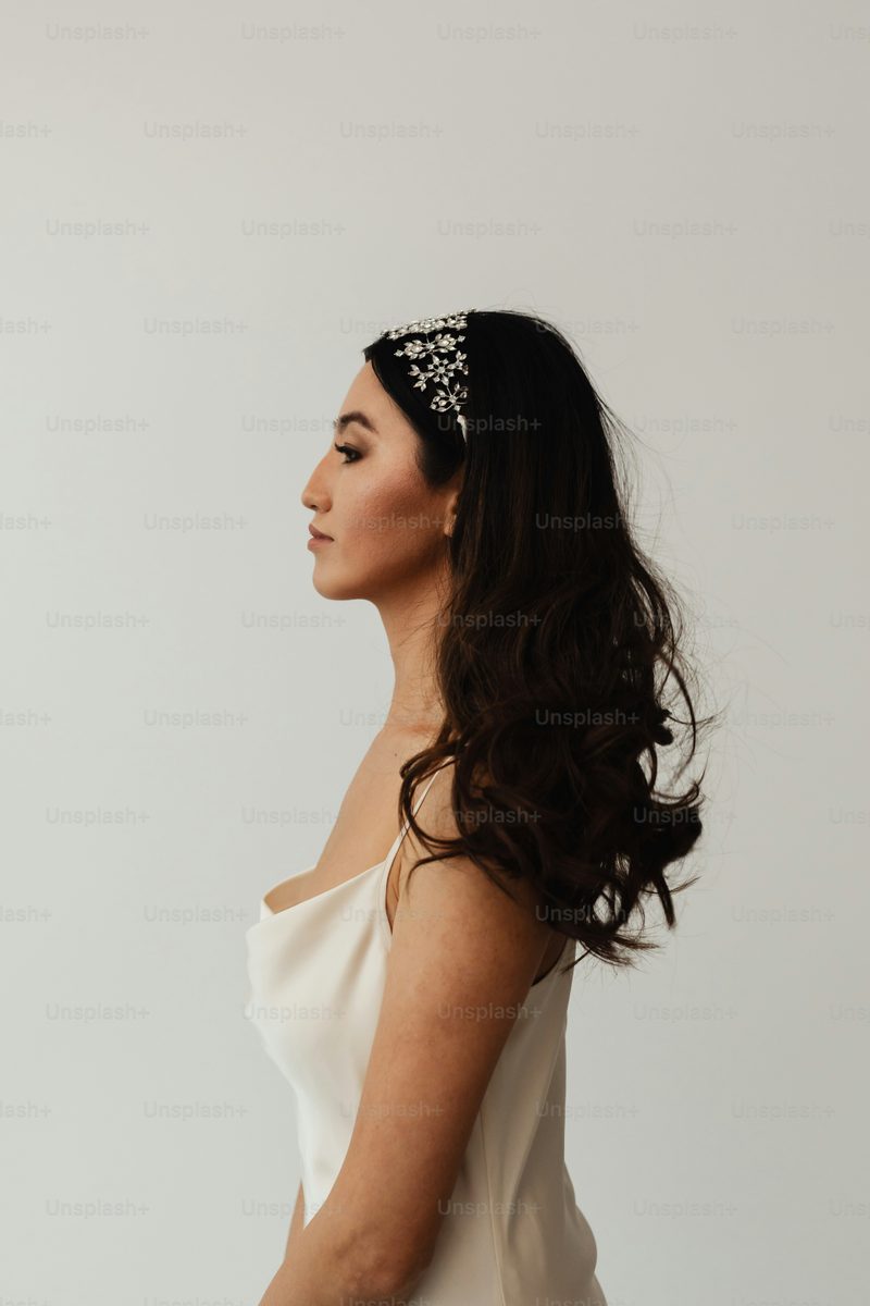 Woman in a white silk dress wearing a crystal-embellished headpiece, elegant styling for a formal lunch or evening event
