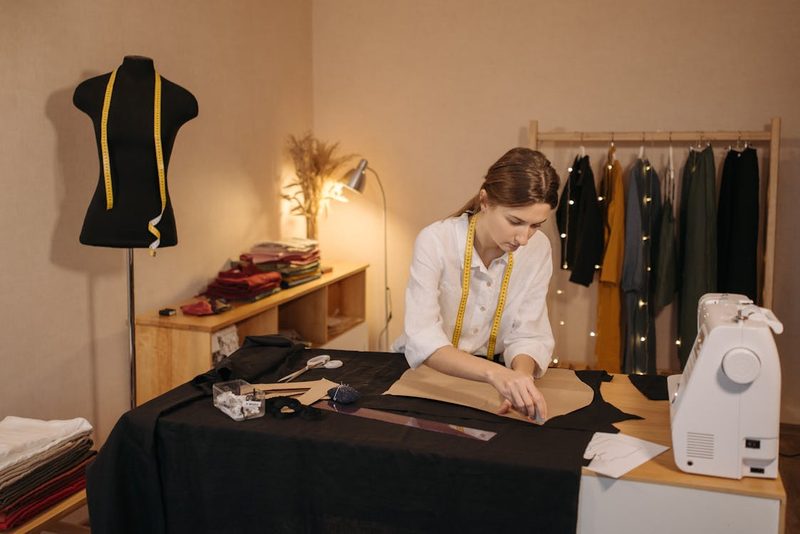 Fashion designer working on a sewing pattern in a couture atelier with mannequin and garments
