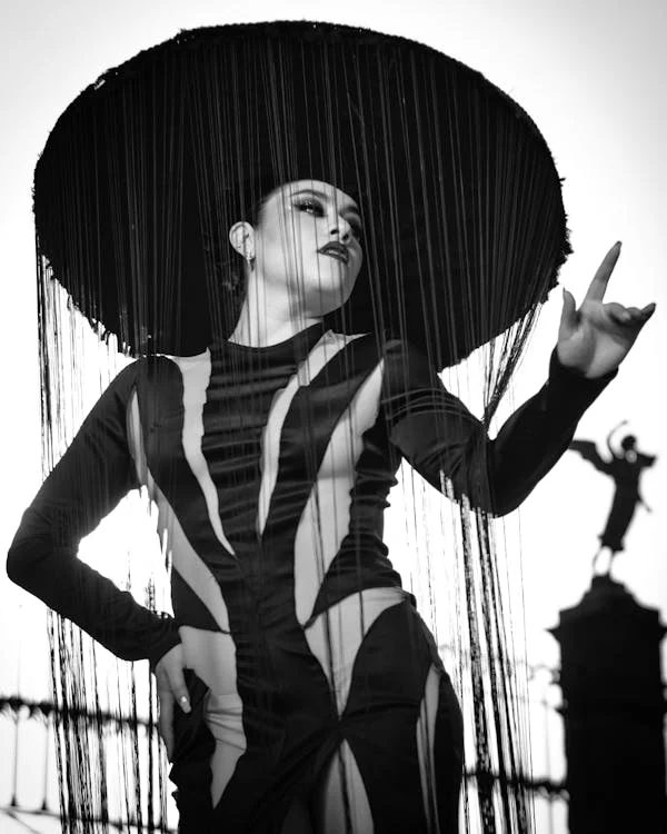 Dramatic artistic fashion portrait featuring a model in an oversized sculptural hat showcasing bold millinery impact