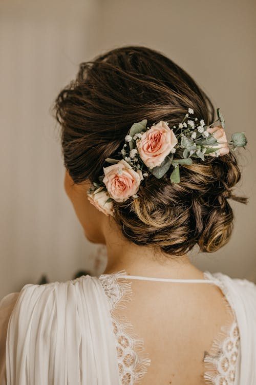 Close-up of an elegant updo adorned with soft pink roses and baby's breath showing delicate detail of a floral hair accessory