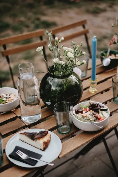 Elegant outdoor picnic table with cake and fresh flowers for a summer garden party celebration