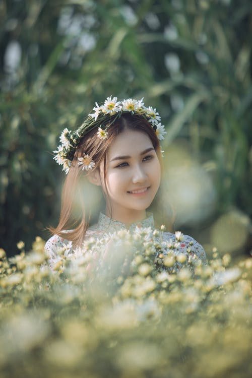 Woman wearing a daisy flower crown in a sunlit garden illustrating a floral halo headpiece as a fresh alternative to a formal hat