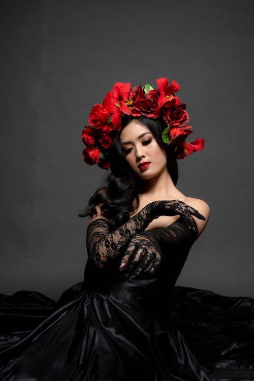 Glamorous woman in a black dress with red floral headdress showcasing haute couture millinery
