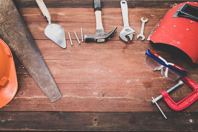 Flat lay of hand tools on a rustic wooden workbench showing traditional crafting instruments