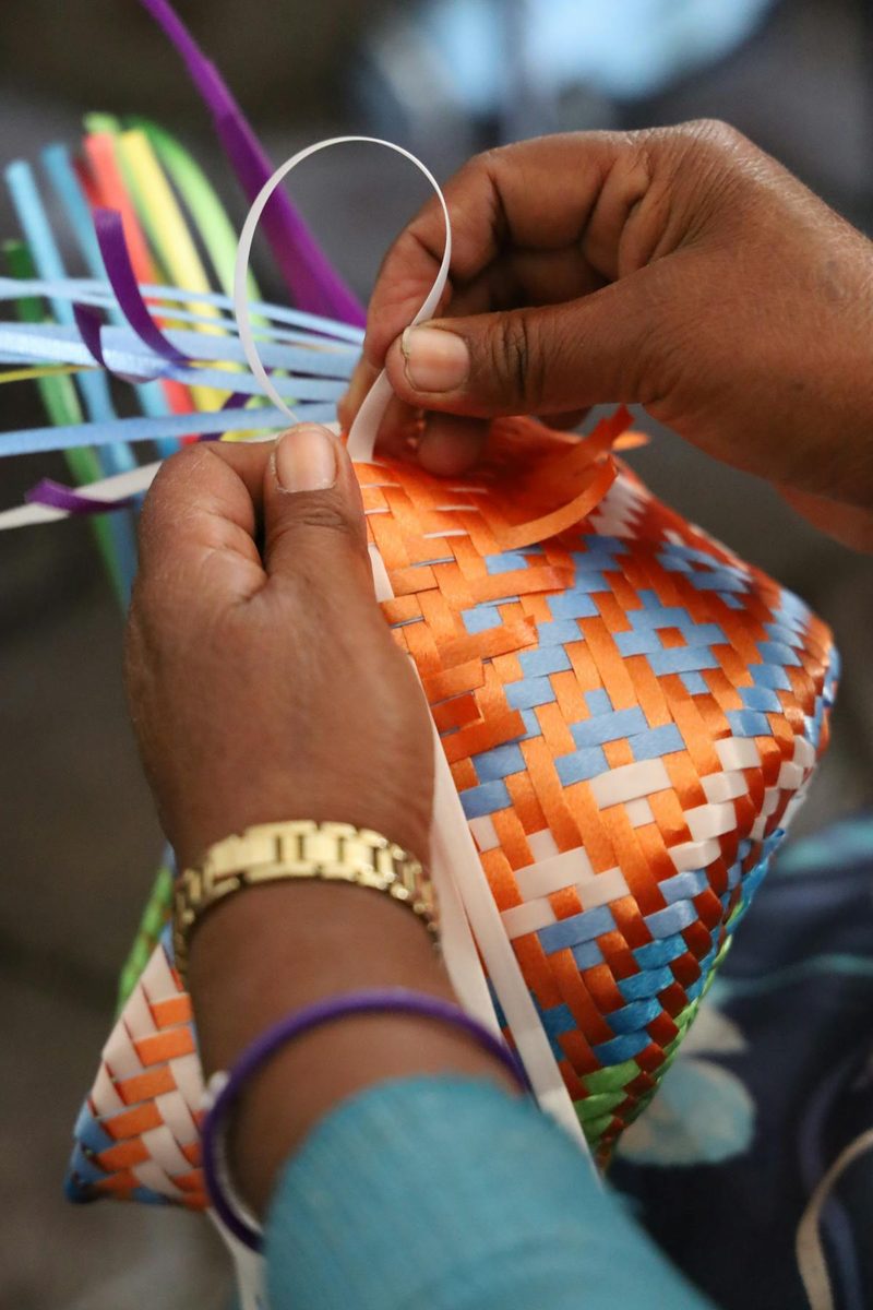 Artisan hands carefully weaving and braiding natural straw fibres demonstrating traditional sustainable handcraft techniques used in millinery