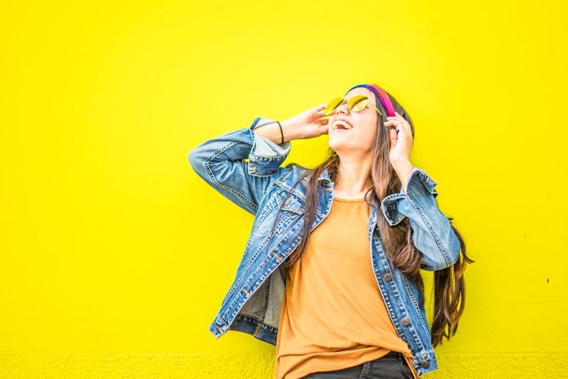 Woman trying on a hat outdoors demonstrating how brim width flatters different face shapes