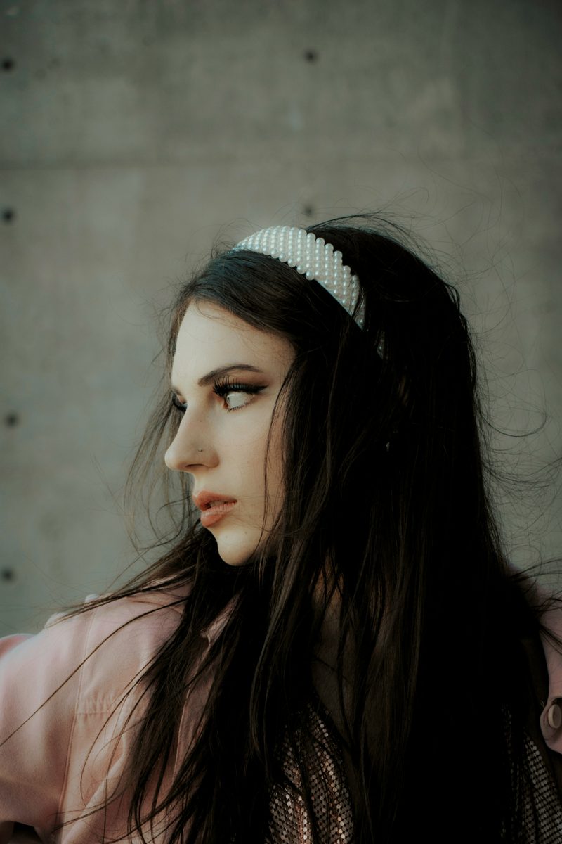 Woman wearing a pearl-studded padded headband paired with a blush pink jacket, a subtle yet stylish accessory for corporate events