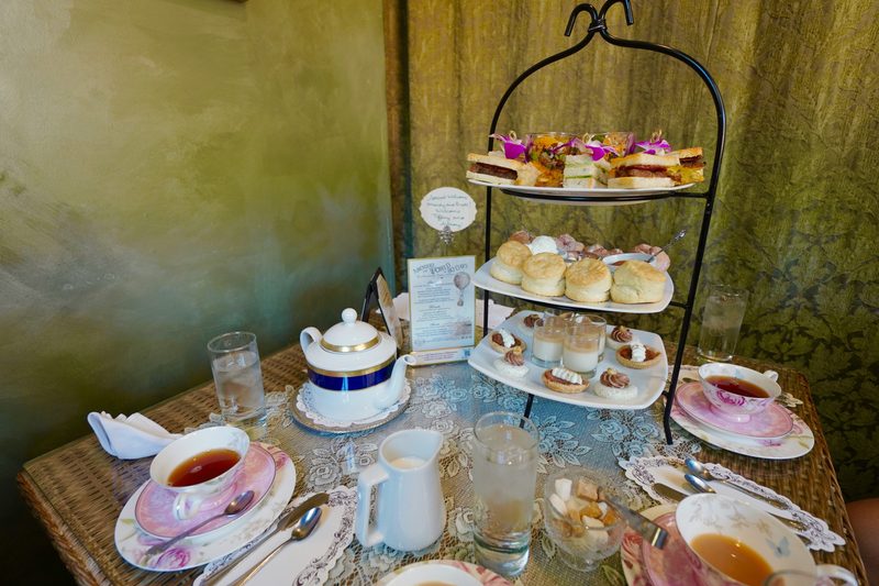 Elegant afternoon high tea setting with tiered stand of scones and pastries, fine china teacups and lace tablecloth