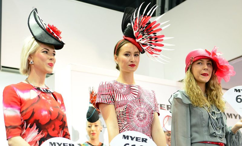 Three finalists at the Melbourne Cup Fashions on the Field competition in colourful racing outfits with statement hats and fascinators