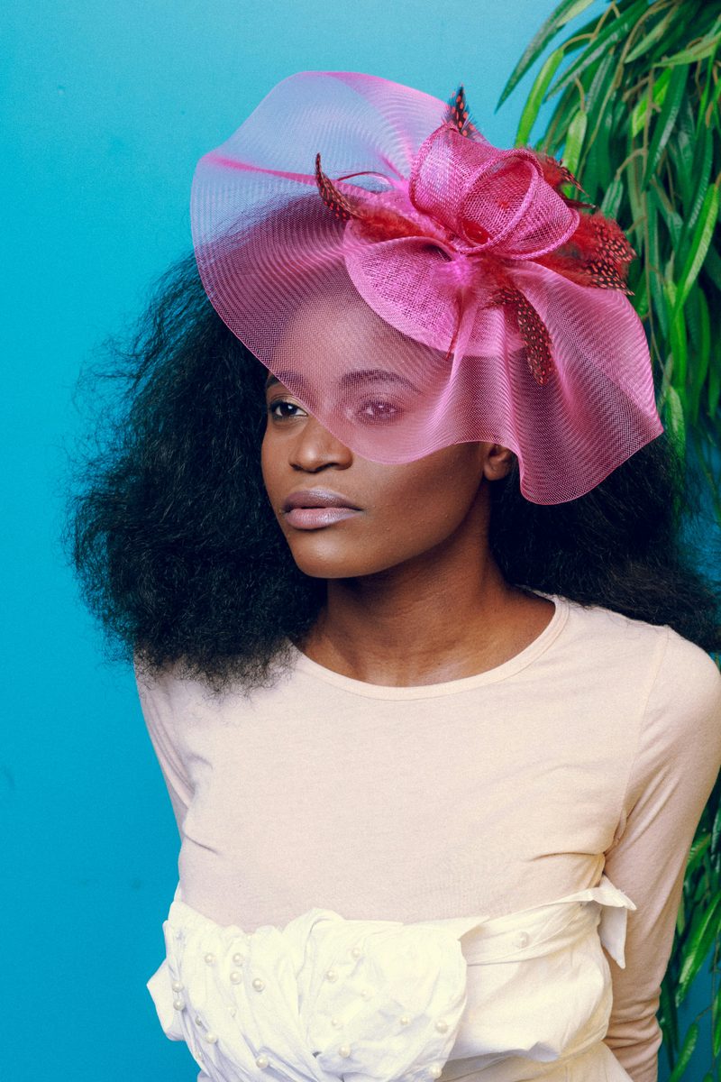 Elegant woman wearing a pink organza fascinator with feather detail styled for a ladies lunch or corporate racing event