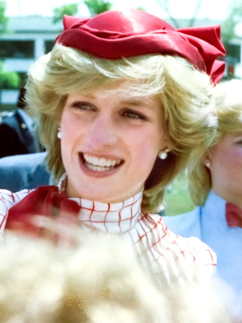 Princess Diana wearing a red hat during her royal visit to Halifax in 1983, showcasing her signature elegant millinery style