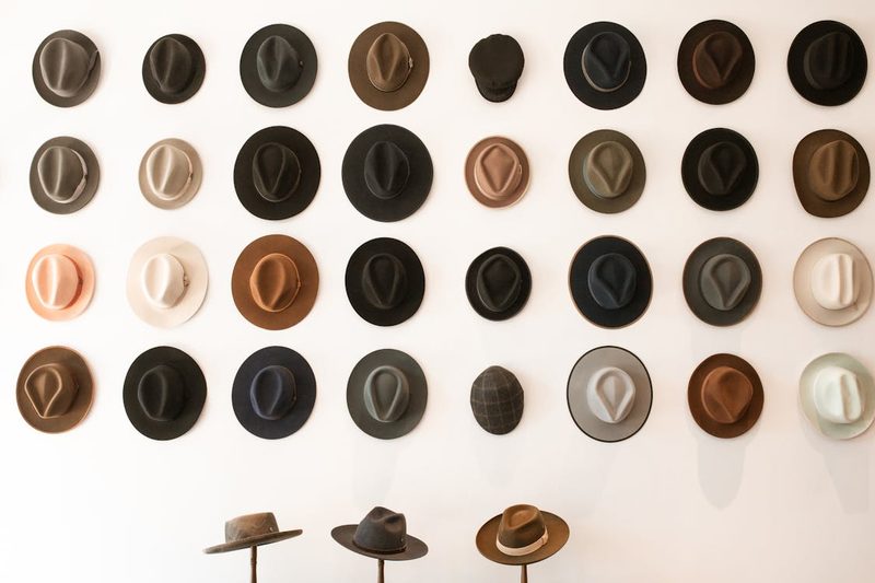 Assorted colourful hats displayed in rows in a boutique showing the range of ready-to-wear headwear available for every occasion