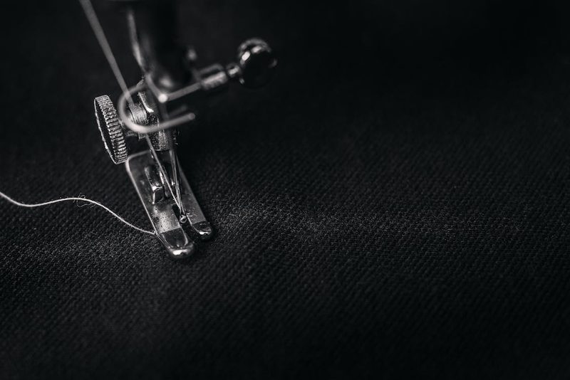 Close-up of a sewing machine presser foot stitching fabric showcasing precision craftsmanship in hat construction