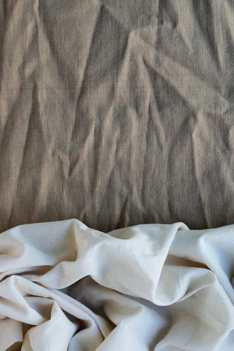 Close-up of layered natural fabric textures in earthy tones representing sustainable organic textiles used in ethical millinery