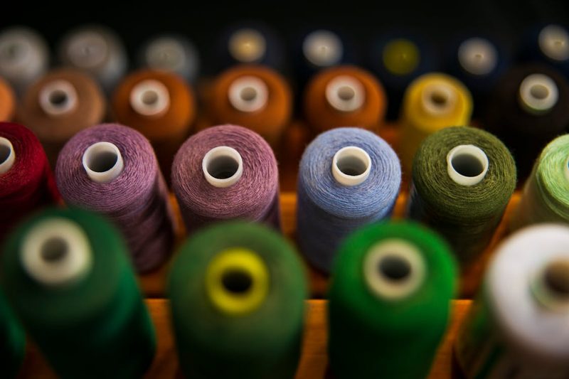 Assorted colourful thread spools and sewing supplies in a milliner workspace ready for bespoke hat creation