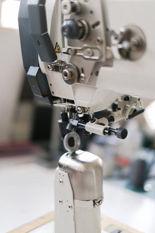 Industrial sewing machine close-up with thread and fabric representing the trimming stage of hat blocking