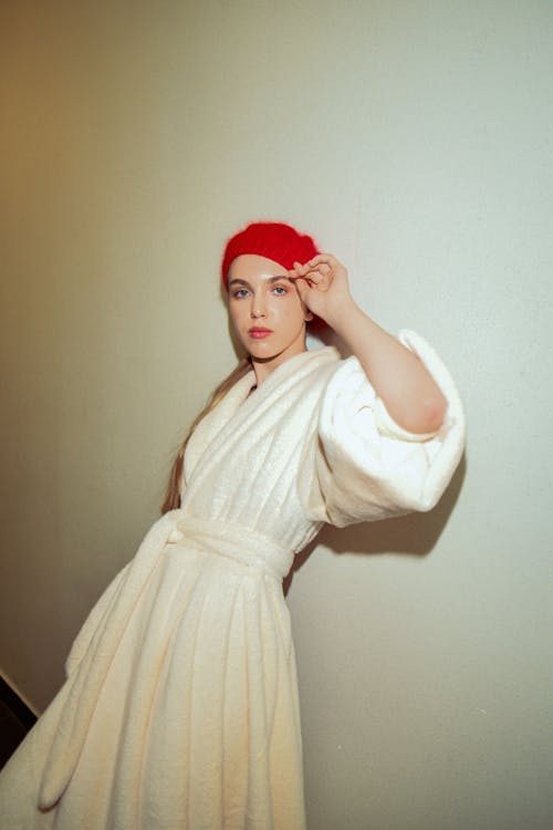 Woman posing in a white dress with a statement red hat for bold colour blocking