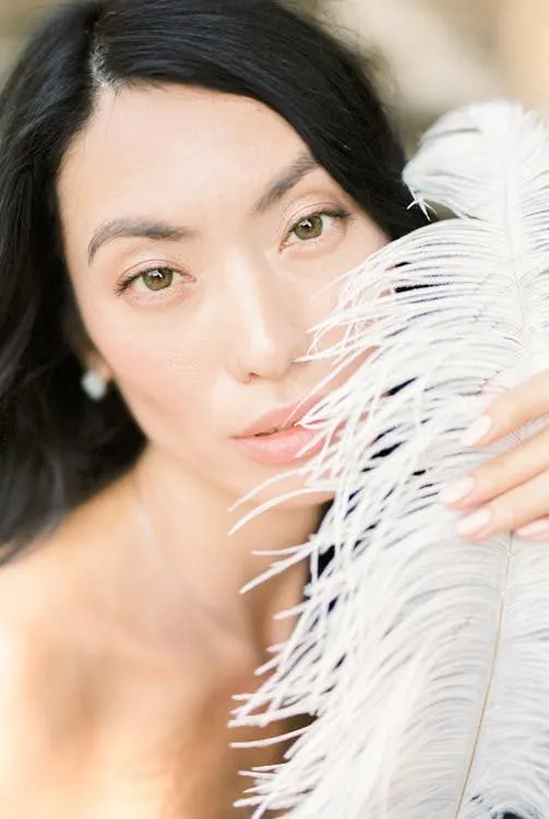 Woman adorned with flowing white feathers evoking the drama of couture feathered headpieces