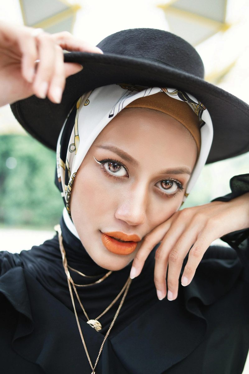 Close-up portrait of a woman wearing a structured dark hat capturing the refined elegance of winter racing headwear