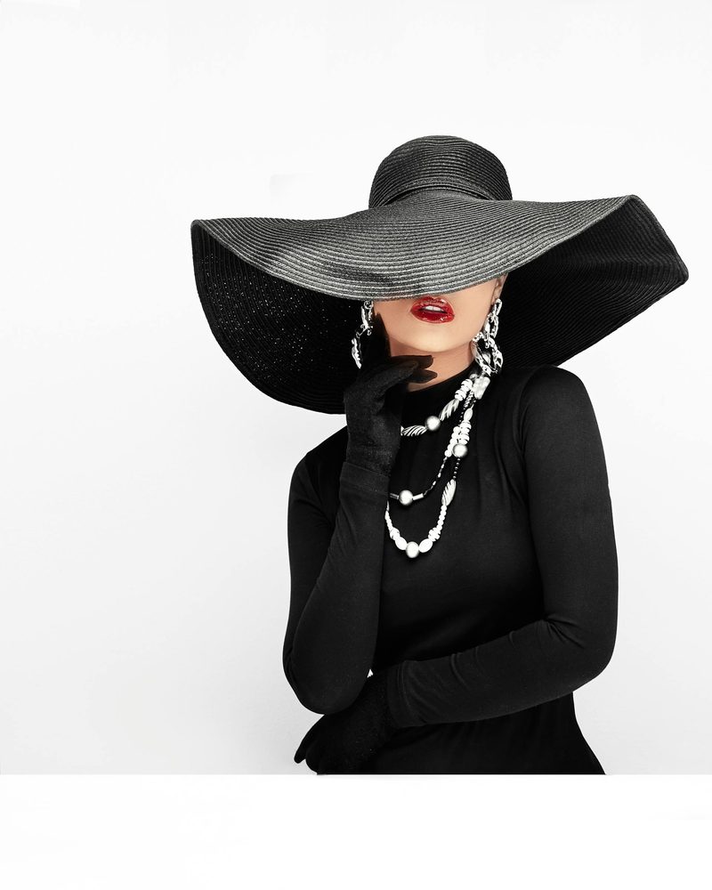 Woman in a structured black wide-brimmed hat and dark outfit evoking the sophistication of winter racing millinery