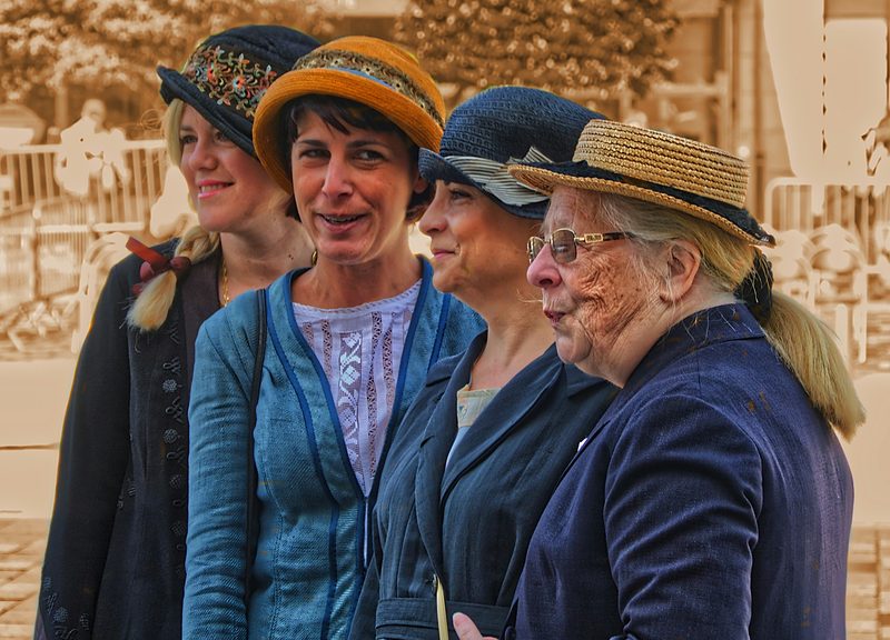 Group of women wearing elegant hats socialising at a stylish outdoor event embodying classic garden party charm