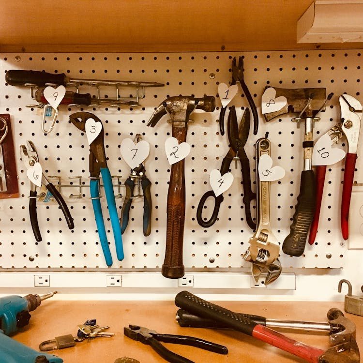 Handheld tools neatly arranged on a pegboard in a well-lit artisan workshop