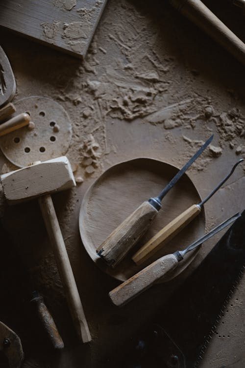 Collection of traditional workshop tools and wooden forms on a bench evoking the hat block maker's craft