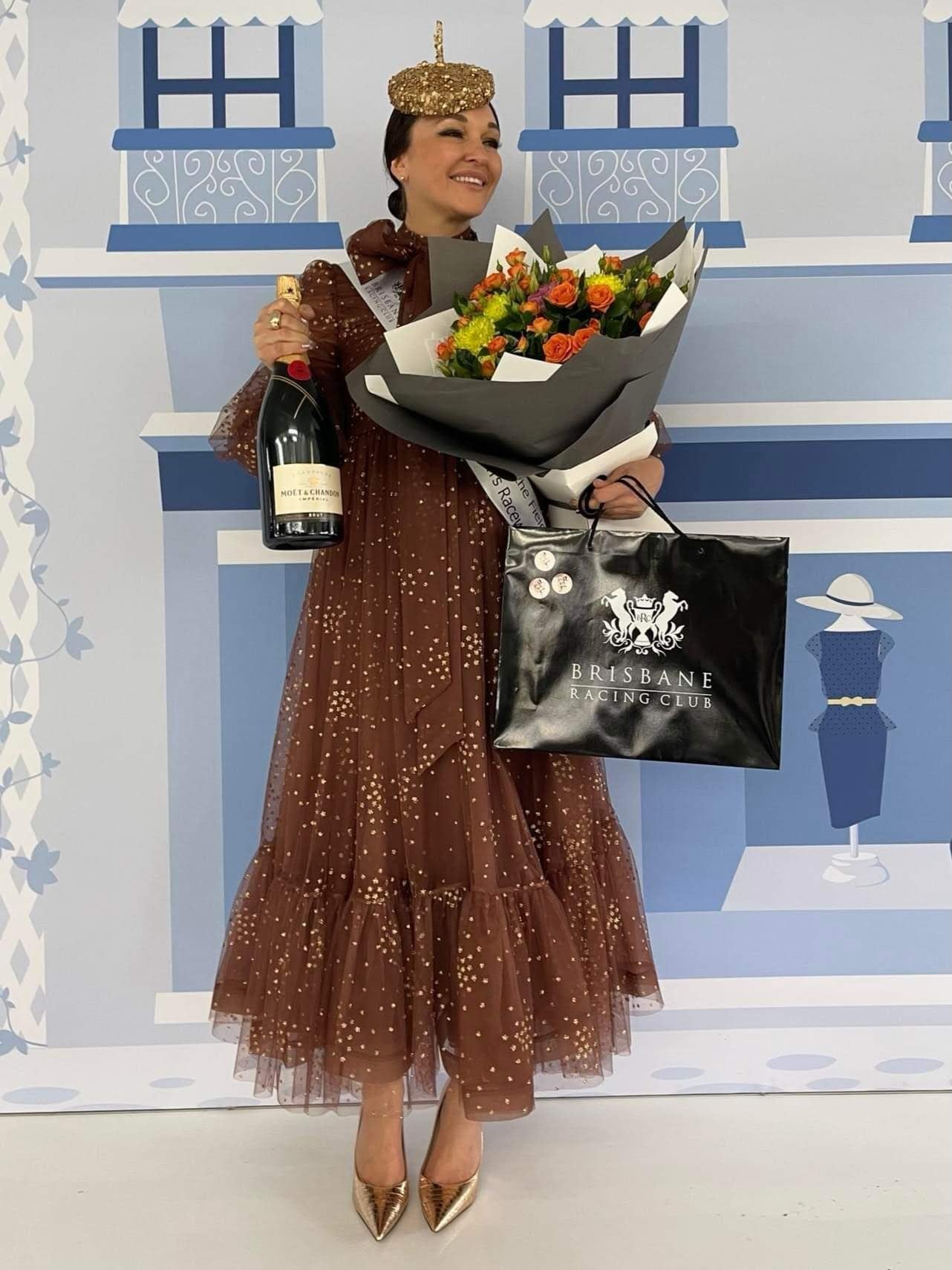 Fashions on the field winner wearing KLM gold crown headpiece at Brisbane Racing Club with Moet champagne and bouquet
