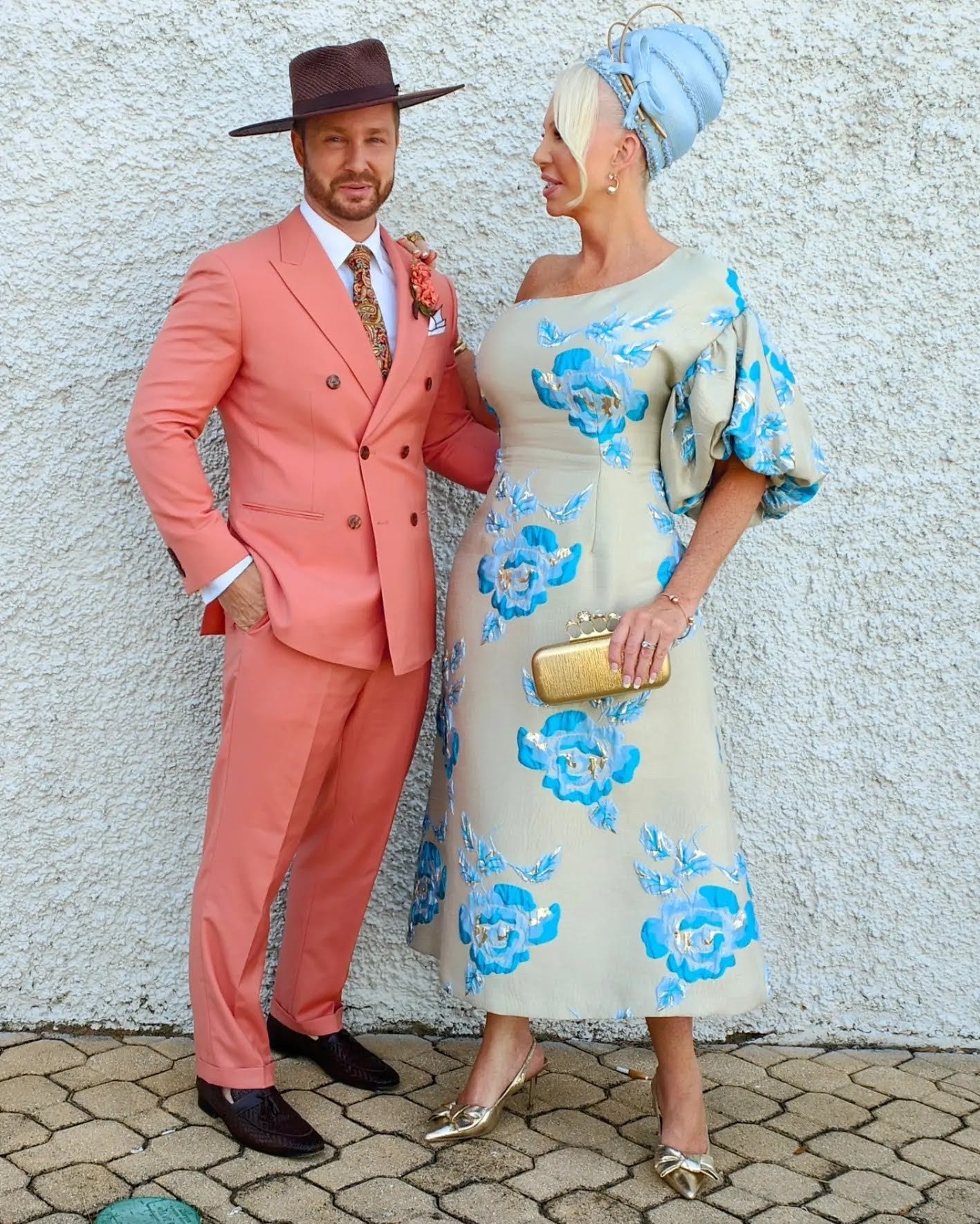 Race day couple - client in blue turban by Kathryn Lee Millinery with coral suit and brown fedora hat