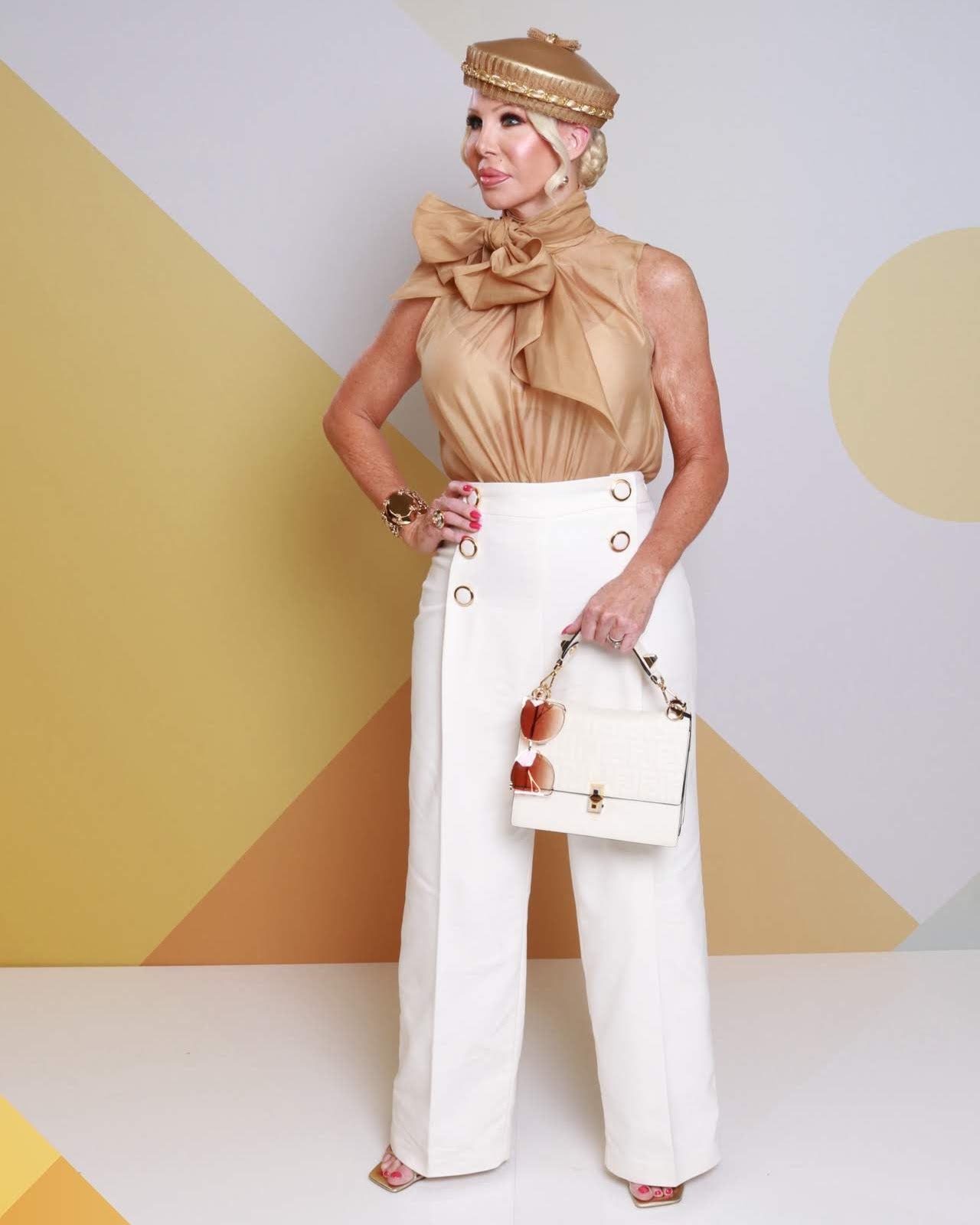 Client wearing gold pillbox hat by Kathryn Lee Millinery with champagne silk bow outfit at the races