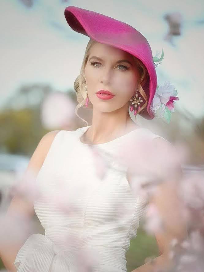 Client wearing a pink straw fascinator with floral detail by Kathryn Lee Millinery at race day